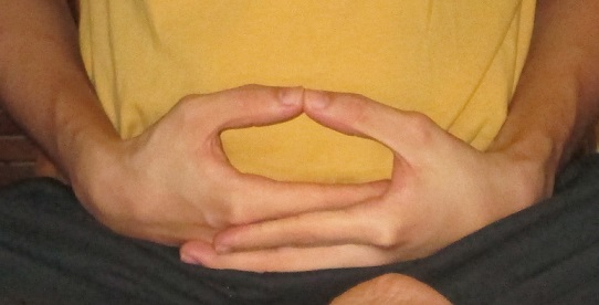 Hands resting in the meditation mudra, right hand over left with thumb tips touching