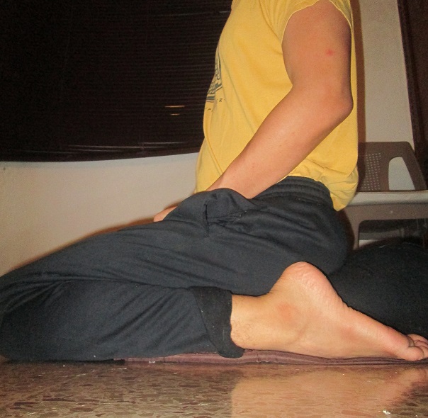 Seiza kneeling meditation posture seen from the side, spine upright above the cushion