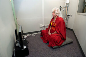 Matthieu Ricard sitting in meditation with electrodes measuring brain signals